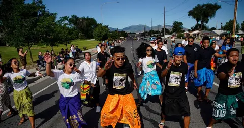 A group of people perform a traditional dance in the street during an outdoor event.