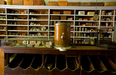 The interior of an old-fashioned general store with shelves and a counter.