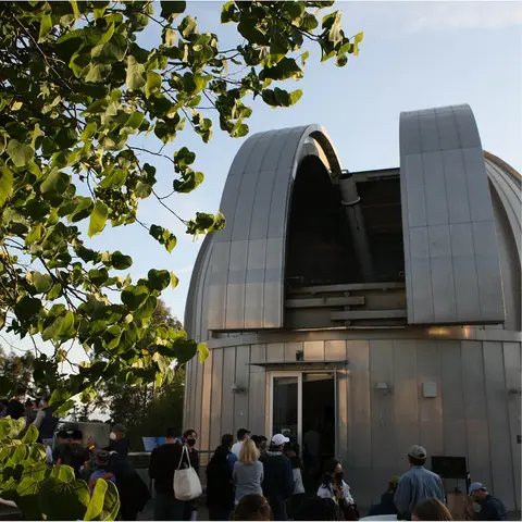 People line up outside the entrance to an observatory dome.