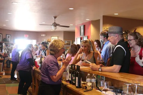 People gather and taste wine at a bar interior.