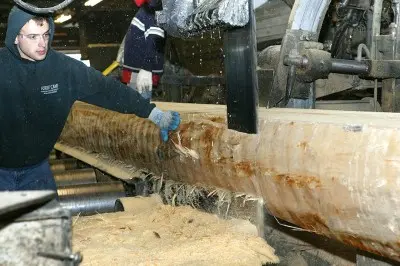 A man working with a large log at a sawmill.