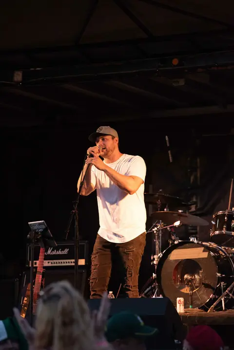 A singer performs on stage with a drum kit behind him.