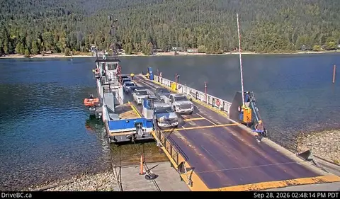 A ferry loaded with vehicles is docked at a ramp.