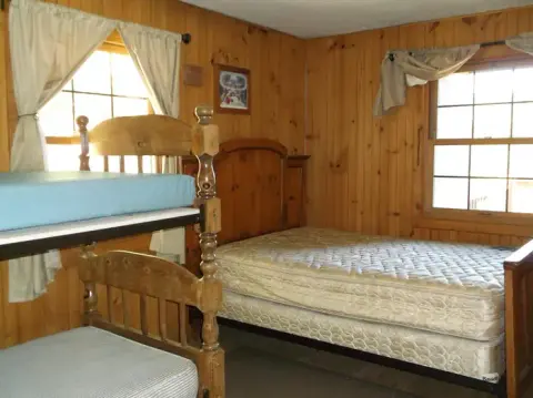 A bedroom with wooden walls and multiple beds.