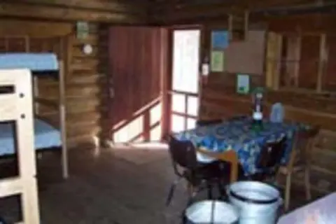 An interior view of a log cabin with a bunk bed and a table.