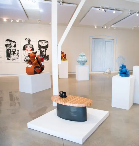 An art gallery displays various sculptures and artwork on white pedestals.