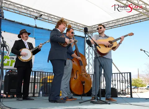 A bluegrass band performs on an outdoor stage.