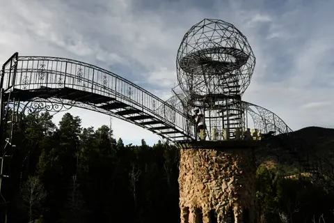 A stone and metal tower with an arched walkway and spherical top structure.