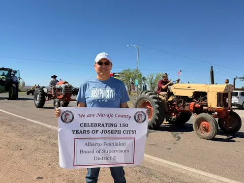 A man holding a banner in front of tractors in a parade.