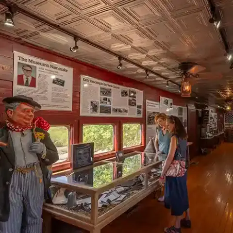 Visitors look at exhibits inside a museum room with a patterned ceiling and red walls.