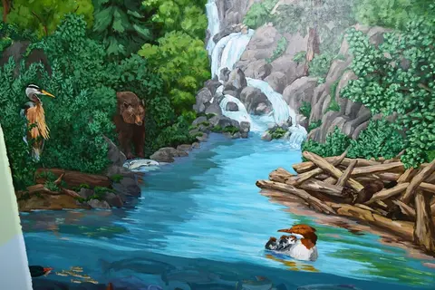A painted mural depicts a waterfall, stream, bear, and various birds.