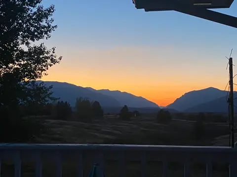 A sunset view over mountains and fields from a porch.