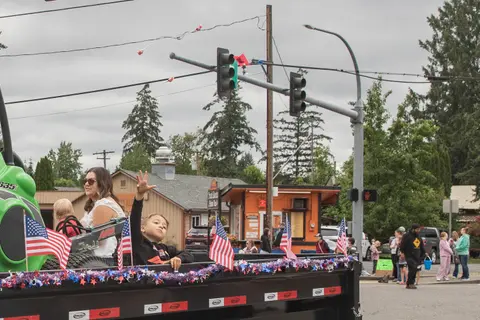 A child waving from a decorated parade float on a street.
