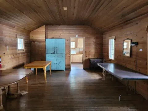 A rustic wooden interior room featuring tables and a blue cabinet.