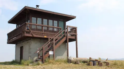 Exterior view of a wooden lookout tower with a concrete base and outdoor stairs.