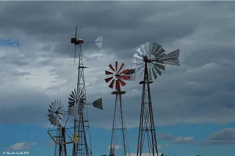 A collection of various old windmills against a cloudy sky.