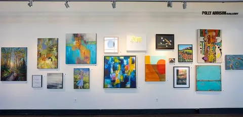 A gallery wall displays numerous paintings and artworks.