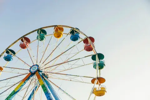 A colorful Ferris wheel is shown against a clear sky.