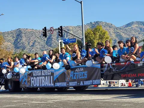 A decorated parade float with students and cheerleaders riding along a street.