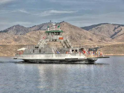 A ferry boat on a body of water with hills in the background.