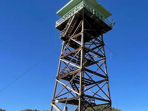 A tall wooden lookout tower stands against a clear blue sky.