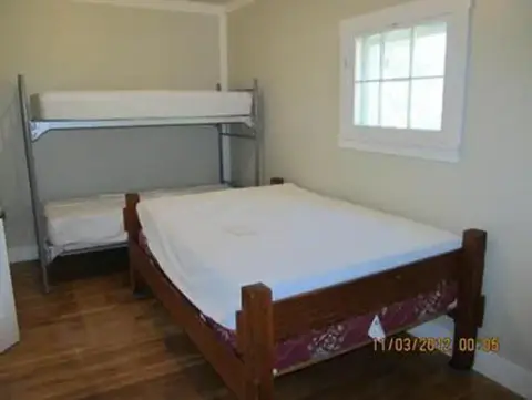 A bedroom with a wooden bed and a metal bunk bed.