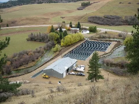 An elevated view of a rural facility with buildings, raceways, and surrounding landscape.
