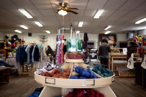A display of colorful yarn stands in the interior of a shop.
