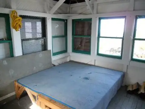 A photo showing the interior of a small cabin with a bed.