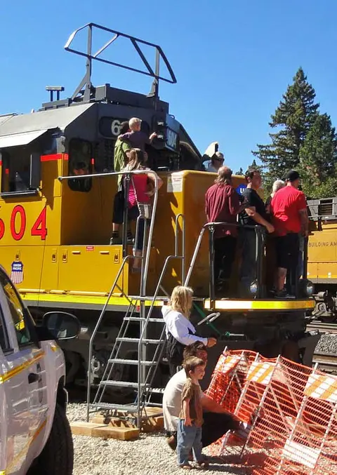 People gather on and around a large locomotive.