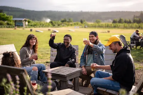 A group of friends sitting outdoors, raising glasses in a toast.