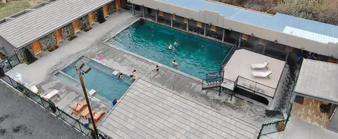 An elevated view of outdoor swimming pools with people swimming and relaxing.