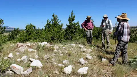 A group of people standing near a rock formation outdoors.