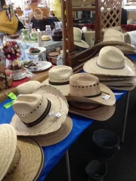 Stacks of straw cowboy hats are displayed on a table indoors.