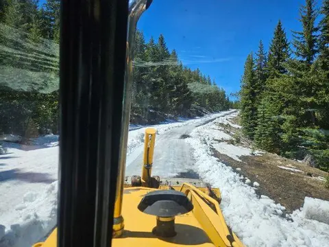 A view from inside a snowplow clearing a snowy mountain road.