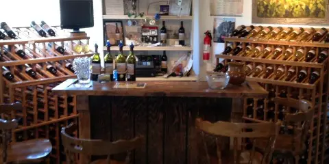 A rustic wine tasting room featuring wooden racks filled with bottles and a tasting counter.