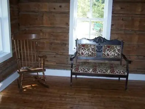 A rocking chair and a settee inside a log cabin room.