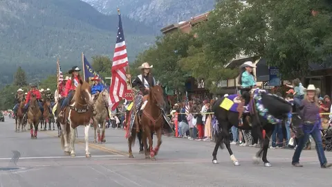 A parade featuring people riding horses down a street.