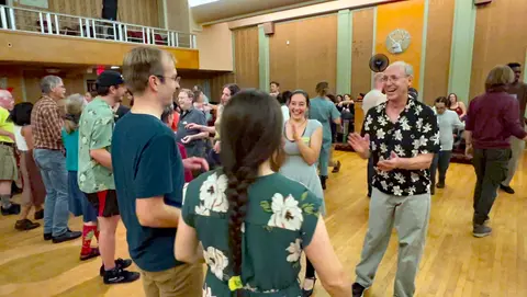 A group of people dancing in a large wooden hall.