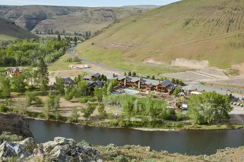 A resort nestled between a river and rolling green hills.