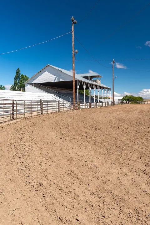 An outdoor rodeo arena with a covered grandstand under a clear blue sky.