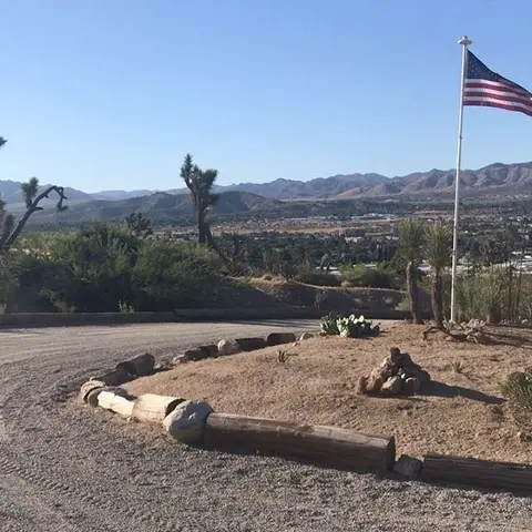 An American flag flies in a desert landscape overlooking a valley.