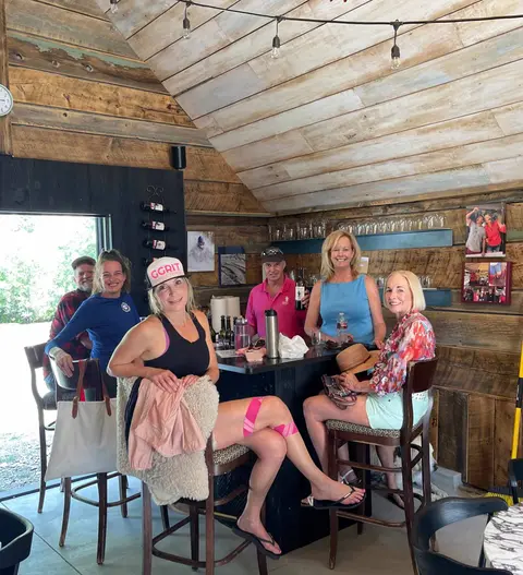 A group of people sitting at a bar inside a rustic wooden cabin.