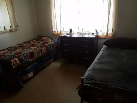 A bedroom with two single beds and a dresser under a window.