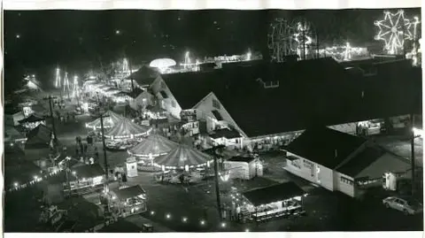 An aerial black and white photo of a carnival or fair at night.
