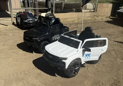 Several toy cars parked on a dirt lot.