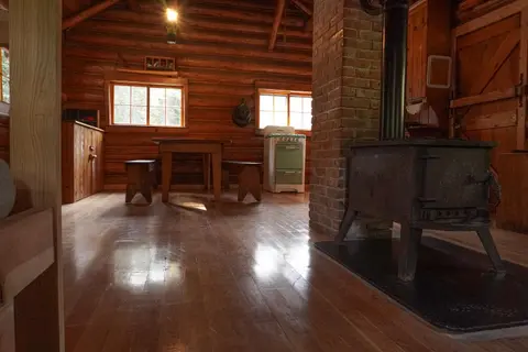 The interior of a rustic log cabin with a wood stove.