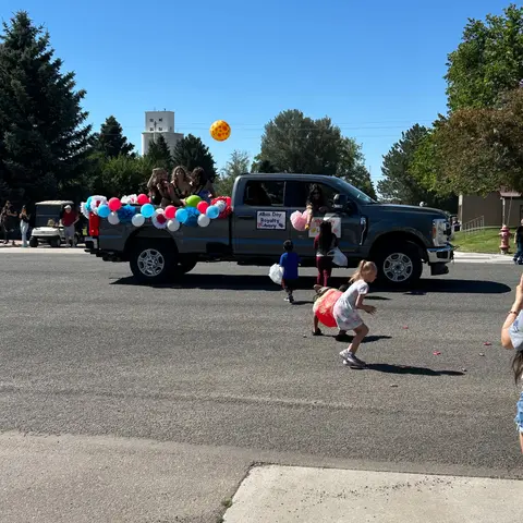 A decorated truck in a parade with people and children walking alongside.