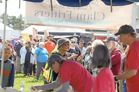 A crowd of people gathers outside under a tent at an event.