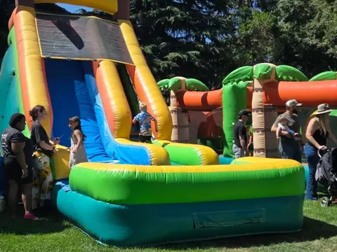 People gather around a large inflatable water slide outdoors.